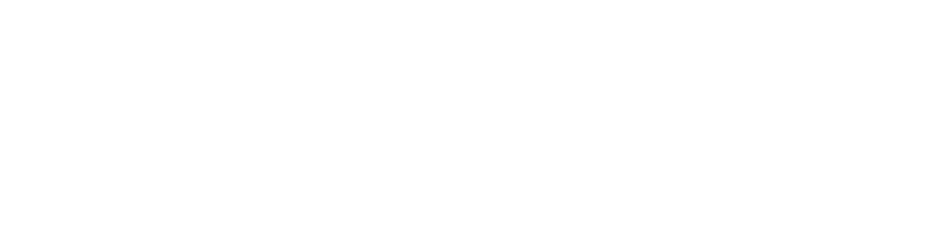 A distinguished older man in a navy suit sits on stacked bundles of fabric against a rustic backdrop, looking serious.